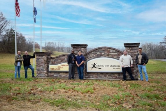 Group of men standing in front of ATC sign
